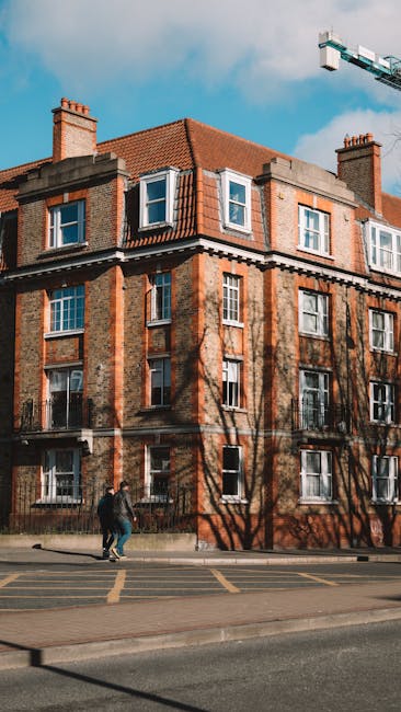 An urban street scene outside a residential building in Bethnal Green with a gently sloping road marked with a 'SLOW' sign in white paint and a designated parking area in blue. The scene shows a mix o